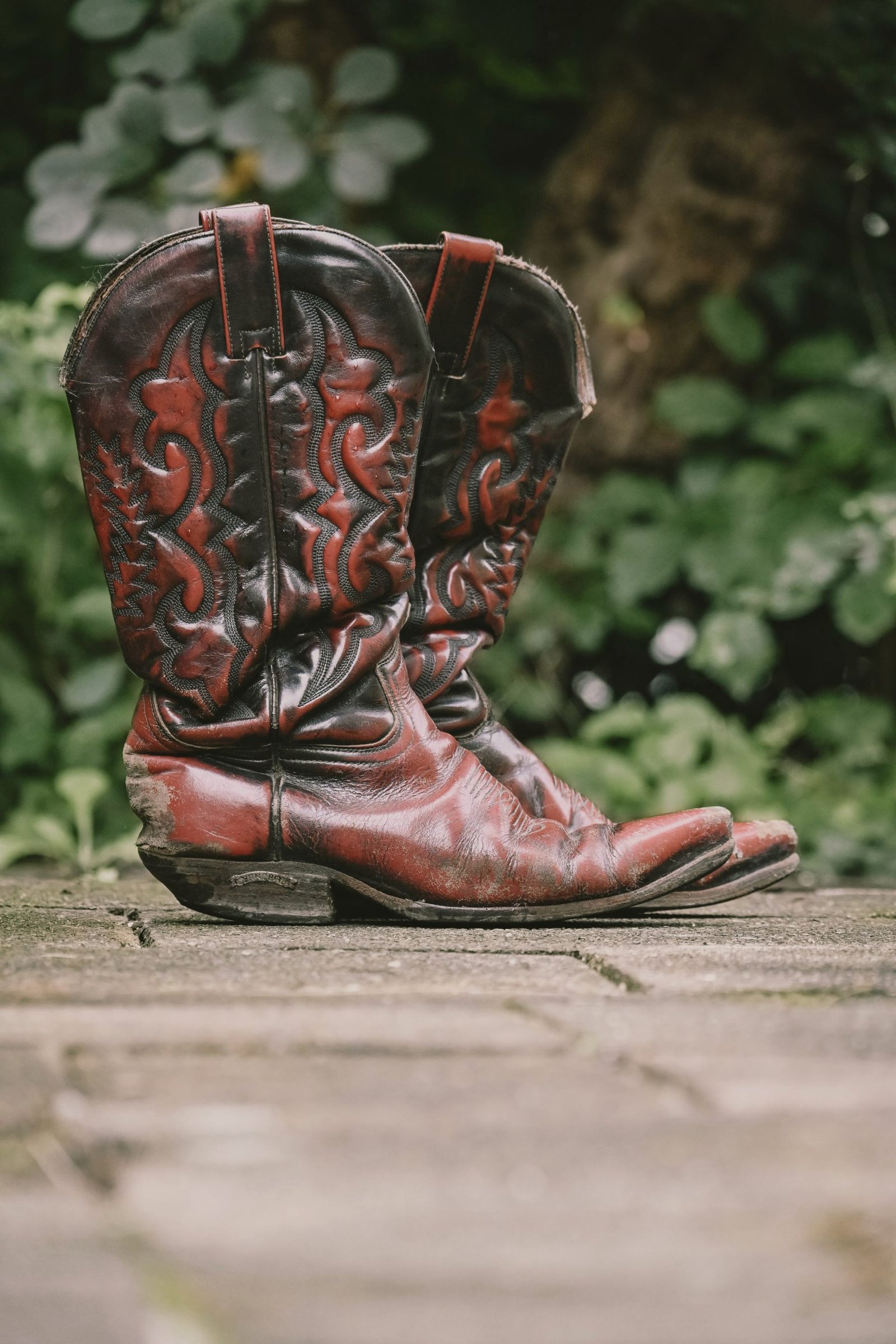 A pair of tooled cowboy boots standing on a path.