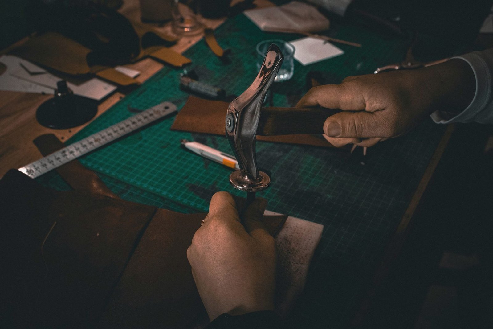 Leather being cut on a bench with a steel rule and knife.